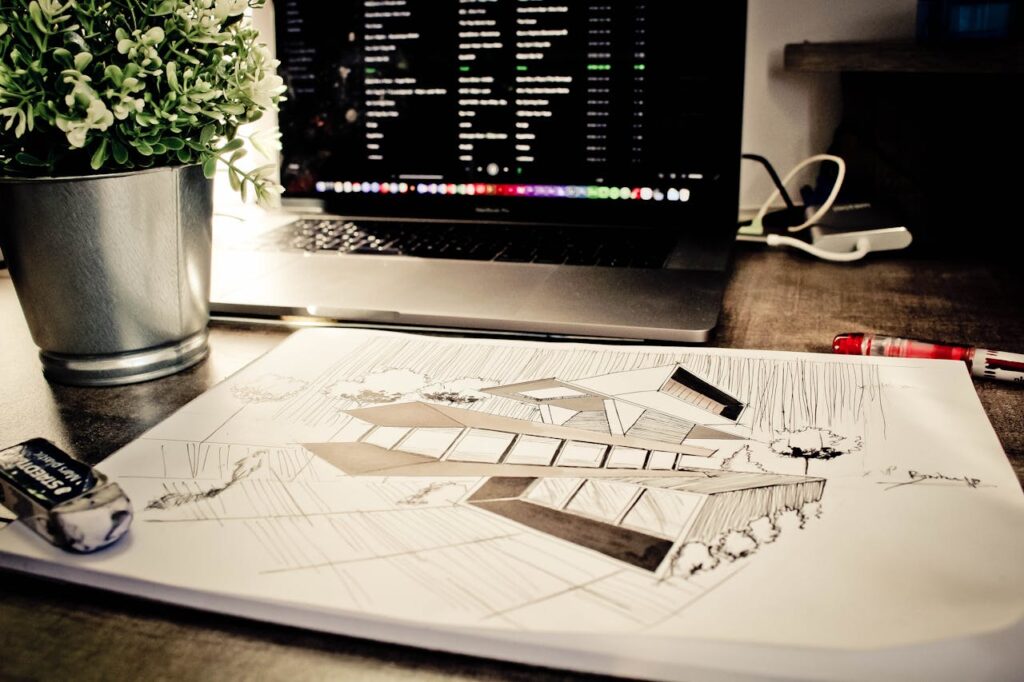 pexels-photo-923307 Architectural sketch on a desk alongside a laptop and plant in an office setting.
